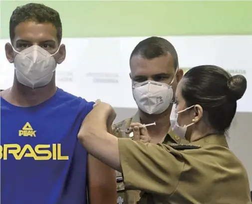  ?? The Yomiuri Shimbun ?? Brazilian archer Marcus D’Almeida, left, receives a COVID-19 vaccine in Rio de Janeiro on May 14.