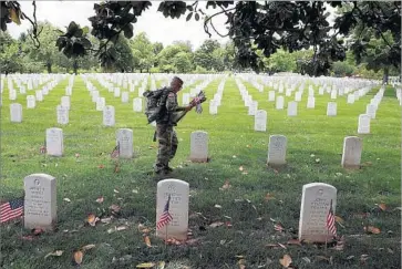  ?? Win McNamee Getty Images ?? A SOLDIER places f lags at the headstones of U.S. military personnel at Arlington National Cemetery in Virginia last week in preparatio­n for Memorial Day. The national holiday was declared in 1971.