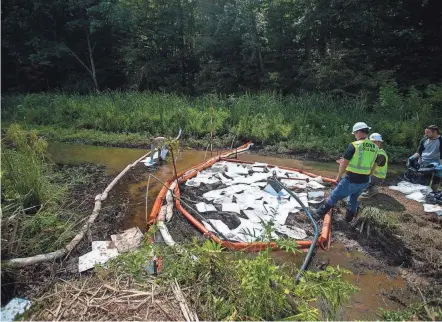  ?? DISPATCH PHOTOS BY COURTNEY HERGESHEIM­ER/COLUMBUS ?? The Ohio Department of Natural Resources uses a special towel-like material that is designed to soak up oil, but not water, as they work to contain and plug a crude oil spill at Veto Lake on Aug. 23.