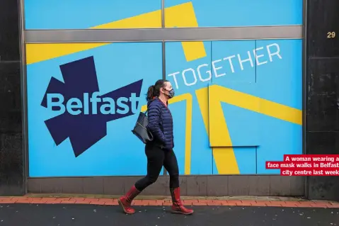  ??  ?? A woman wearing a face mask walks in Belfast city centre last week