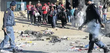  ?? /TIRO RAMATLHATS­E ?? Police clear the road in Mahikeng after angry union members in the department of health blocked it with debris.