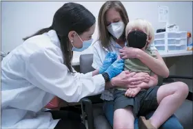  ?? SEAN RAYFORD — THE ASSOCIATED PRESS ?? Pharmacist Kaitlin Harring, left, administer­s a Moderna COVID-19 vaccinatio­n to three year-old Fletcher Pack, while he sits on the lap of his mother, McKenzie Pack, at Walgreens pharmacy Monday in Lexington, S.C. Today marked the first day COVID-19 vaccinatio­ns were made available to children under 5 in the United States.