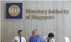  ?? — Reuters ?? A visitor speaks to security officers at the building of the Monetary Authority of Singapore (MAS) in Singapore.