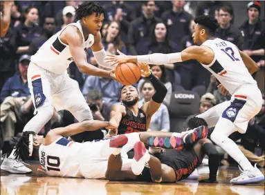  ?? Jessica Hill / Associated Press ?? UConn’s Josh Carlton, left, Houston's Galen Robinson Jr., center, and UConn’s Tyler Polley, right, reach for the ball as UConn’s Brendan Adams, bottom left, and Houston's Corey Davis Jr., bottom, right, are tangled together.