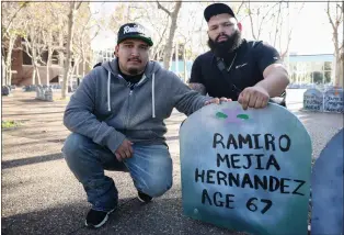  ?? SHAE HAMMOND — STAFF PHOTOGRAPH­ER ?? Luis Mejia,24, of San Jose, and his brother Vidal Mejia, 29, of San Jose, sit next to their uncle Ramiro Mejia Hernandez's tombstone at the Santa Clara County building in San Jose during an annual memorial for all unhoused people who died over the past year.