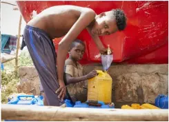  ??  ?? BELOW: Brothers Douale Mahadi and Ali Farha collect clean water provided by Oxfam