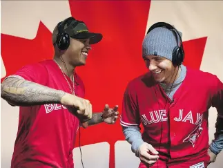  ?? CHRIS YOUNG/THE CANADIAN PRESS ?? Toronto Blue Jays teammates Marcus Stroman, left, and Ryan Goins listen to music for a social media stream and model the club’s new red alternate jerseys Friday at the Rogers Centre.