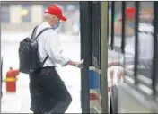  ?? JOHN J. KIM/CHICAGO TRIBUNE ?? A CTA passenger wears a face mask to combat the spread of the coronaviru­s as he boards a No. 151 Sheridan bus on West Adams Street on May 14 in Chicago.