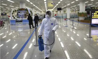  ?? Photograph: Jon Chol Jin/AP ?? A worker in protective gear carries a disinfecta­nt spray can through a nearly deserted terminal at Pyongyang airport.