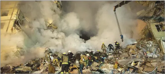  ?? (AP/Evgeniy Maloletka) ?? Emergency workers clear the rubble Jan. 14 after a Russian rocket hit a multistory building leaving many people under debris in the southeaste­rn city of Dnipro, Ukraine.