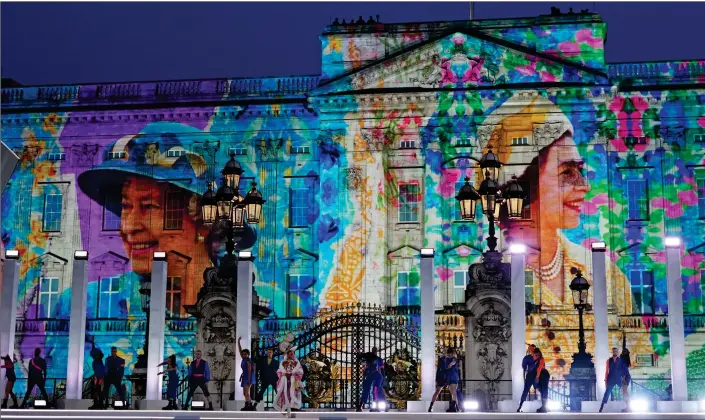  ?? ?? PROUD TRIBUTE: Colourful images of the Queen are projected on to Buckingham Palace’s facade to form a stunning backdrop as dancers delight the crowd during the evening’s celebratio­ns