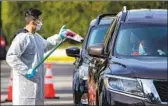  ?? Gina Ferazzi Los Angeles Times ?? A HEALTHCARE worker hands out a coronaviru­s test kit at a drive-through site in Riverside.