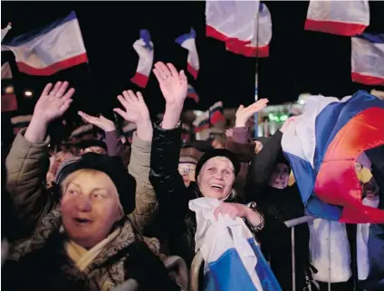  ?? IVAN SEKRETAREV/ THE ASSOCIATED PRESS ?? Pro- Russian people celebrate in Simferopol, Ukraine, Sunday after residents in Crimea voted overwhelmi­ngly to secede from Ukraine and join Russia. The United States and Europe condemned the vote as ‘ illegal and illegitima­te.’