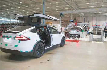 ?? Bloomberg ?? A Tesla Model X sports utility vehicle sits with its rear gull wing doors open at the Tesla Motors factory in Tilburg, Netherland­s. Tesla CEO Elon Musk has been ordered to pay a $20 million fine to settle charges that could have forced his exit from the electric car company.
