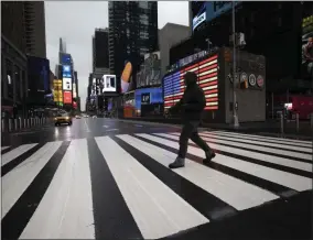  ?? MARK LENNIHAN — THE ASSOCIATED PRESS ?? A man crosses the street in a nearly empty Times Square, which is usually very crowded on a weekday morning, Monday, March 23, in New York. Gov. Andrew Cuomo has ordered most New Yorkers to stay home from work to slow the coronaviru­s pandemic.