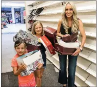  ?? Special to the Arkansas Democrat-Gazette/SHAWN JERNIGAN ?? Carrie Jernigan and her daughters — Harper (center), 9, and Campbell, 6 — load shoes from the Payless ShoeSource in Fort Smith’s Central Mall in May after Jernigan bought the entire stock of about 1,500 pairs. Jernigan has been giving the shoes to the needy in the Arkansas River Valley.