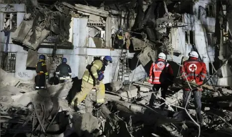  ?? Kateryna Klochko/Associated Press photos ?? Ukrainian State Emergency Service firefighte­rs inspect a damaged house Thursday after Russian shelling in Zaporizhzh­ia, Ukraine. Three people were killed when a Russian missile hit this five-story apartment building.