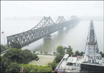  ?? Emily Wang The Associated Press ?? Visitors on Sept. 9 walk across the Yalu River Broken Bridge, right, next to the Friendship Bridge connecting China and North Korea in Dandong.