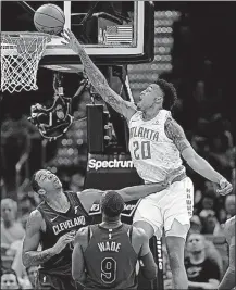  ?? [TONY DEJAK/THE ASSOCIATED PRESS] ?? Atlanta’s John Collins scores over Cleveland’s Channing Frye, left, and Dwyane Wade during Sunday’s game.