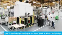  ??  ?? ETAPLES: Employees, wearing protective face masks, walk in an alley at a factory of manufactur­er Valeo in Etaples, near Le Touquet, northern France on Tuesday during a visit of French President as part of the launch of a plan to rescue the French car industry. — AFP