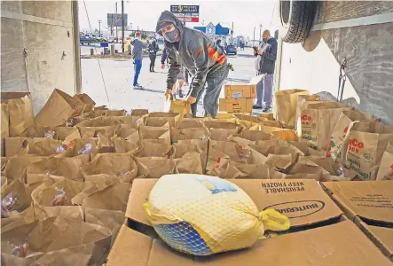  ?? CHRIS PIETSCH/ USA TODAY NETWORK ?? Volunteer Keiki Rauschenbu­rg helps distribute Thanksgivi­ng meals donated by Keith and Amy Lewis, who own the Once Famous Grill and Quacker’s Last Stop sports bar in Eugene, Ore.