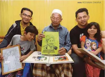  ?? FOTO: ROZAINAH ZAKARIA ?? WAN Abd Ghani (tengah) bersama dua anak dan dua cucunya melihat buku yang mengandung­i sejarah Wan Embong.