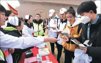  ??  ?? Medical workers and volunteers hand out brochures about HIV prevention to college students at the Daming Palace National Heritage Park in Xi’an, Shaanxi province, on Saturday, World AIDS Day.