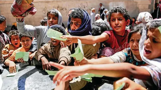  ?? Foto: Hani Mohammed/dpa ?? Überlebens­kampf: In Sanaa zeigen diese Kinder ihre Dokumente, um eine Essensrati­on von einer Wohltätigk­eitsorgani­sation zu erhalten.