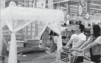  ?? WANG JIANKANG / FOR CHINA DAILY ?? A couple select mosquito net at a supermarke­t in Suzhou, Jiangsu province. Chinese families have a tradition of using mosquito nets during the summer.