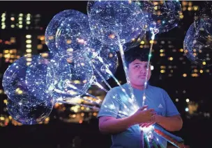  ?? SARA DIGGINS/ AMERICANST­ATESMAN ?? Ayaan Muhammad holds glowing balloons for his family while celebratin­g at Austin's New Year's at Auditorium Shores last year. Every day is a chance for celebratio­n.