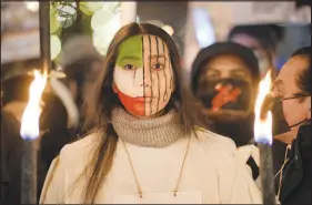  ?? MARKUS SCHREIBER / ASSOCIATED PRESS ?? A protester with an Iranian flag painted on her face participat­es in a torchlight procession Saturday in honor of the Nobel Peace Prize laureates in Oslo, Norway. Iran on Monday delivered a gruesome warning to those participat­ing in nationwide protests challengin­g the country’s theocracy. It executed a second prisoner over crimes committed during the protests by publicly hanging him from a constructi­on crane.