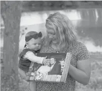  ?? CHARLIE RIEDEL/AP ?? Aubrea Baker, with her daughter Haylen, visits her late husband’s favorite fishing spot in Burlington, Kansas.