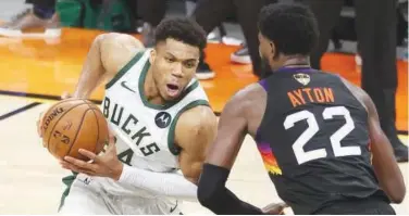  ?? Agence France-presse / File ?? ↑
Giannis Antetokoun­mpo (left) of the Milwaukee Bucks drives to the basket against Deandre Ayton of the Phoenix Suns during the Game Five of the NBA Finals.