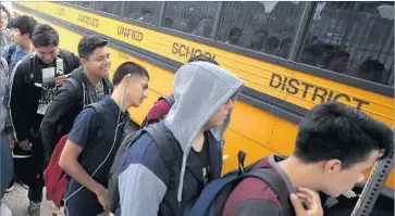  ?? Mark Boster Los Angeles Times ?? JEFFERSON HIGH school students wait at a bus stop on the first day of classes in August. Under a new agreement, students in L.A. Unified probably can start taking community colleges classes in the spring.