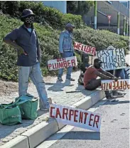  ?? Picture:SUNDAY TIMES ?? LOOKING FOR WORK: A group of unemployed men seen with signage of the skills they have as they try to get piece jobs