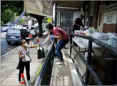  ?? MATT SLOCUM — THE ASSOCIATED PRESS ?? In this June 11, 2020, photo Lourdes Sherby, center, with Guadalupe Family Services, hands diapers to Louisa Peralta in Camden, N.J. “I think we’re received a lot better than we used to be,” said Sgt. Dekel Levy, 41, as he helped hand out diapers to a steady stream of young mothers Thursday afternoon at Guadalupe Family Service.