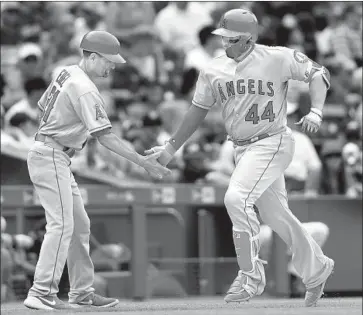  ?? Matthew Stockman Getty Images ?? THE ANGELS’ RENE RIVERA is congratula­ted by third-base coach Dino Ebel after hitting a solo home run in the seventh inning against the Colorado Rockies at Coors Field. The blast gave the Angels a five-run lead.