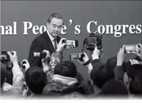  ??  ?? Photograph­ers take snapshots of China’s Foreign Minister Wang Yi leaving the stage after a press conference on the sidelines of the National People’s Congress at the media center in Beijing, Thursday.