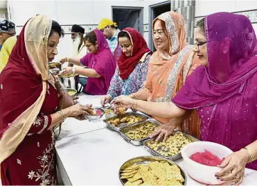  ??  ?? Volunteer Jagjit Kaur, 65, (right) offering sweet treats to the late politician Karpal Singh’s wife Gurmit Kaur (left) during the Vaisakhi celebratio­n at the Wadda Gurdwara Sahib in Jalan Gurdwara in Penang. Right: Hindu devotees going through their...
