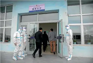  ?? AP ?? Security officers in protective suits hold the doors as government officials enter the visitors’ hall at the Urumqi No. 3 Detention Centre in Dabancheng in western China’s Xinjiang Uyghur Autonomous Region.