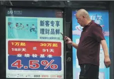  ?? AN XIN / FOR CHINA DAILY ?? A man walks past a billboard advertisin­g a bank’s wealth management products in Tongling, Anhui province.