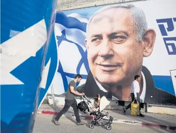  ??  ?? A man walks by an election campaign billboard showing Israel’s Prime Minister Benjamin Netanyahu in Tel Aviv.AP