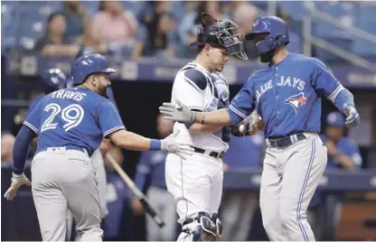  ??  ?? Teoscar Hernández, a la derecha, de los Azulejos, celebra con Devon Travis, luego de pegar un jonrón de dos carreras frente a Ryan Yarbrough, de Tampa Bay, en el tercer inning durante la tercera entrada en St. Petersburg.