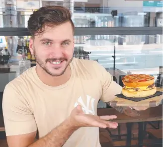  ?? Picture: RICHARD GOSLING ?? Jacob Low with a ‘Bizzaro’ pizza burger at Brooklyn Depot.