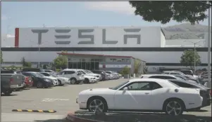  ?? The Associated Press ?? TESLA: Vehicles are seen parked at the Tesla car plant Monday, in Fremont, Calif. The parking lot was nearly full at Tesla's California electric car factory Monday, an indication that the company could be resuming production in defiance of an order from county health authoritie­s