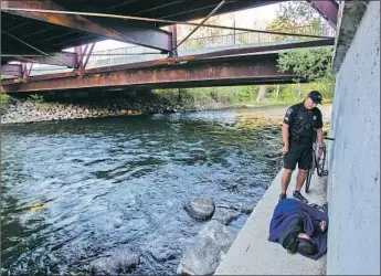  ?? Photograph­s by Otto Kitsinger For The Times ?? SGT. CRAIG NIXON talks to a homeless man by the Boise River in Idaho. Boise’s mayor is contesting a 9th Circuit ruling that upended an anti-camping law. The city and county of L.A. have backed Boise’s bid.