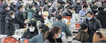  ?? PROTECTION:
Chinatopix via AP ?? Shoppers wearing face masks pay for their groceries at a supermarke­t in Wuhan in central China’s Hubei province.
Pictures: