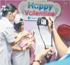  ?? — AFP photo ?? Anchalee Bunsiri, 36 (second left), holds her four day old baby girl Anyada before a Valentine’s Day photoshoot at Paolo Chokchai 4 Hospital in Bangkok.