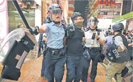  ??  ?? Dos oficiales de la policía de Hong Kong se enfrentaro­n contra los manifestan­tes en el barrio de Mongkok, en el norte de la ciudad.