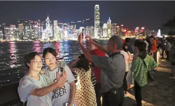  ??  ?? Fewer tourists: Chinese tourists take selfies near the evening skyline of Hong Kong. Paranoid they could be targeted in the leaderless protests and wary after seeing footage of vandalised subway stations, Chinese tourists are staying away this year. — AP